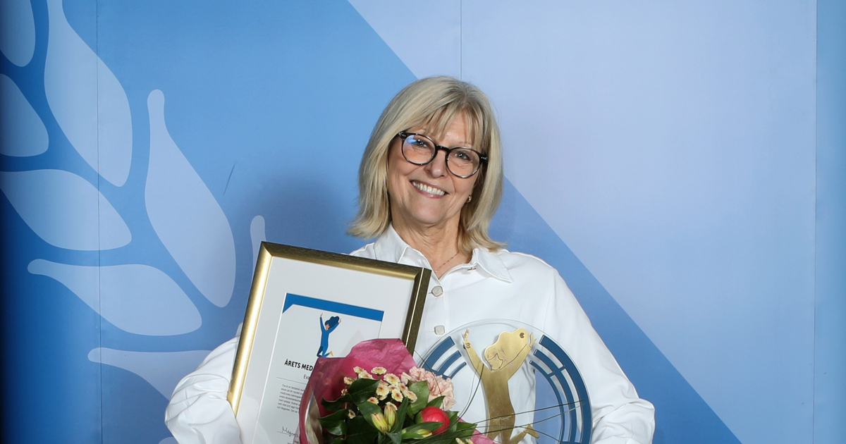 En kvinna håller en blombukett framför en kuliss.