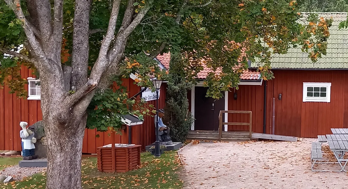 Ett rött hus med ett träd framför sig.