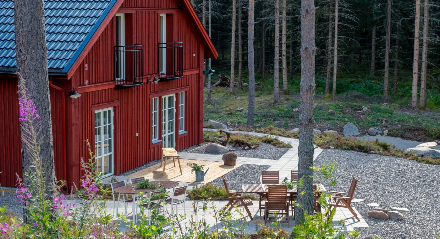 Ett rött hus mitt i skogen.