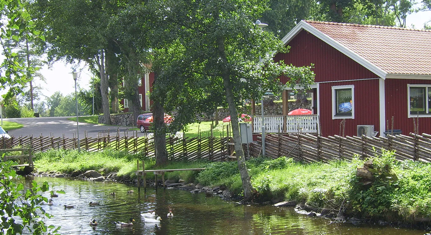 Ett litet rött hus som ligger vid en flod.