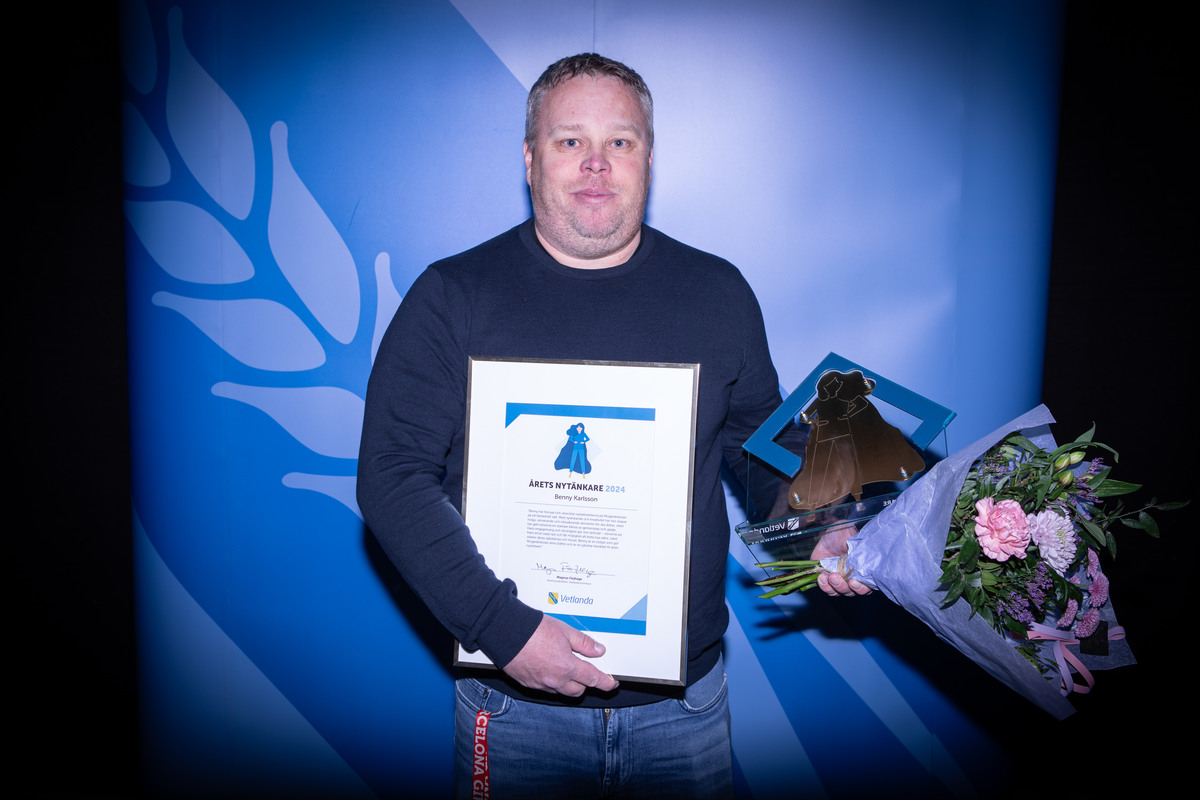 En man håller i ett diplom, en statyett och en blombukett.