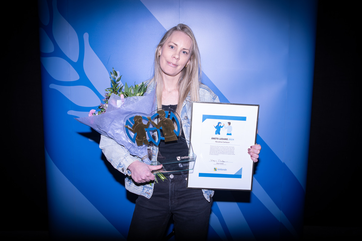 En kvinna håller i en blombukett, en statyett och ett diplom