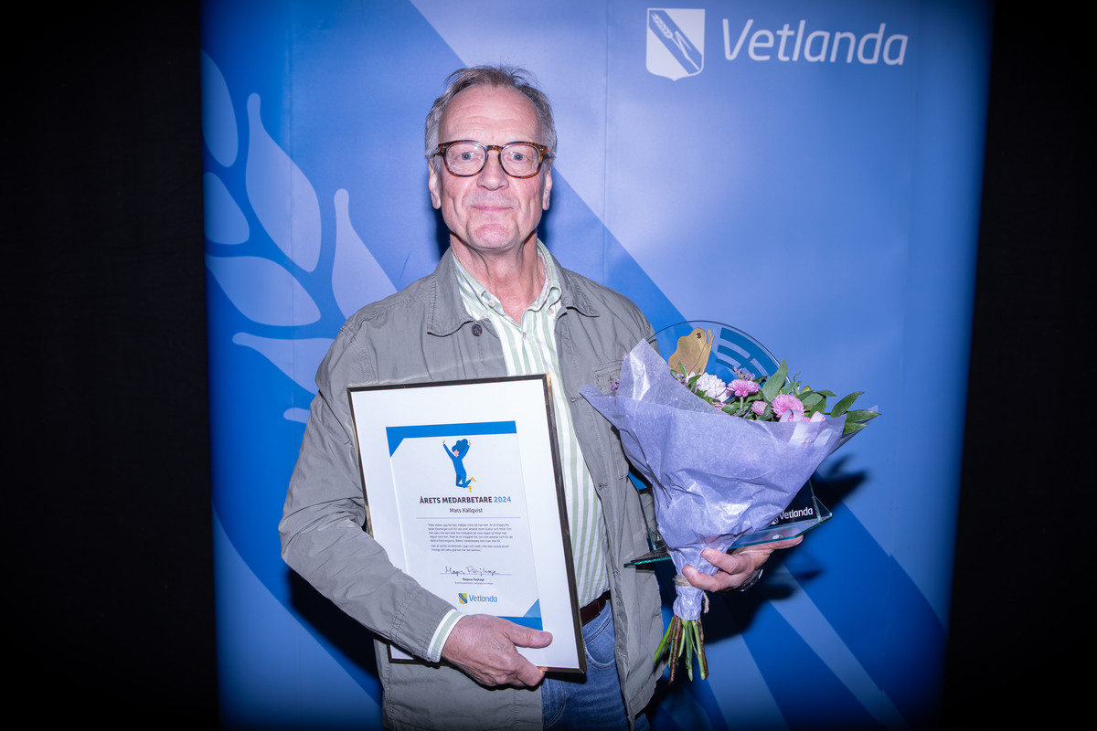 En man håller i ett diplom och en blombukett.