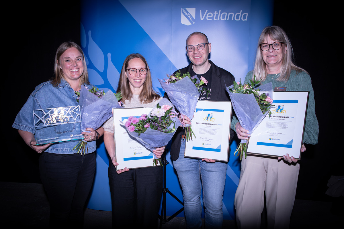 Fyra personer, tre kvinnor och en man håller i diplom och blombuketter. En av dem håller i en statyett.