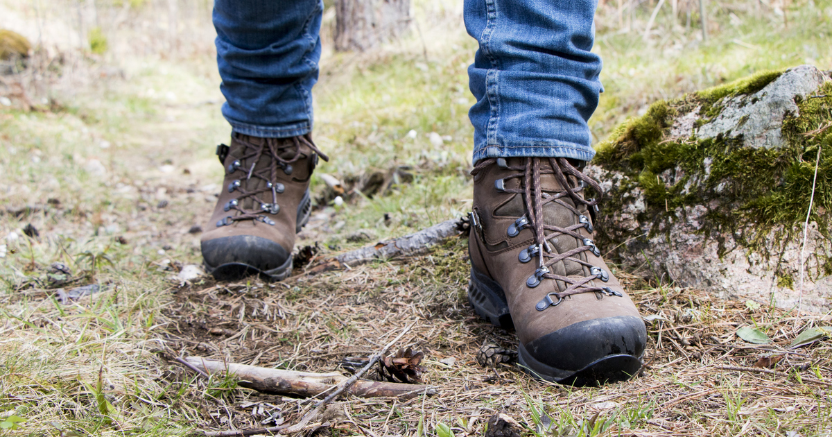 Två fötter med vandringskängor i skogen.