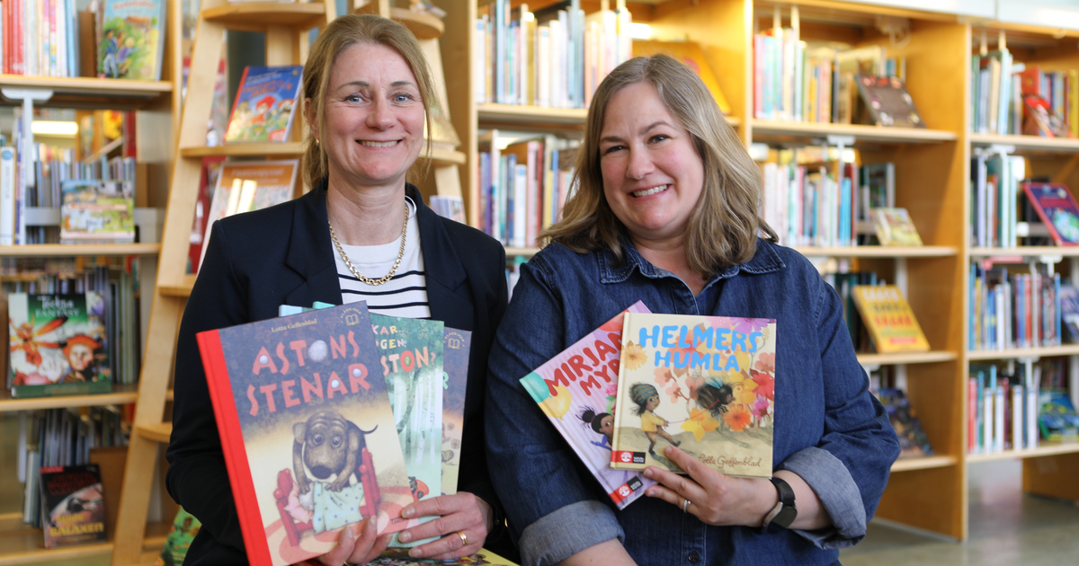 Två kvinnor sitter på biblioteket med famnen full av bilderböcker.