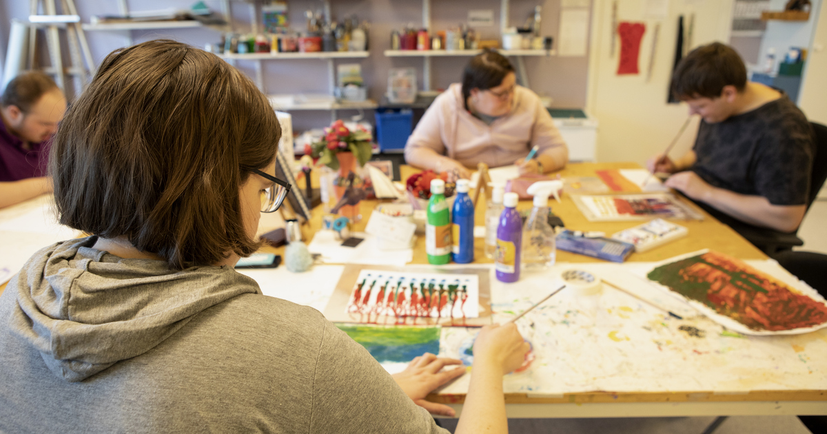 Personer som sitter runt ett bord och målar.