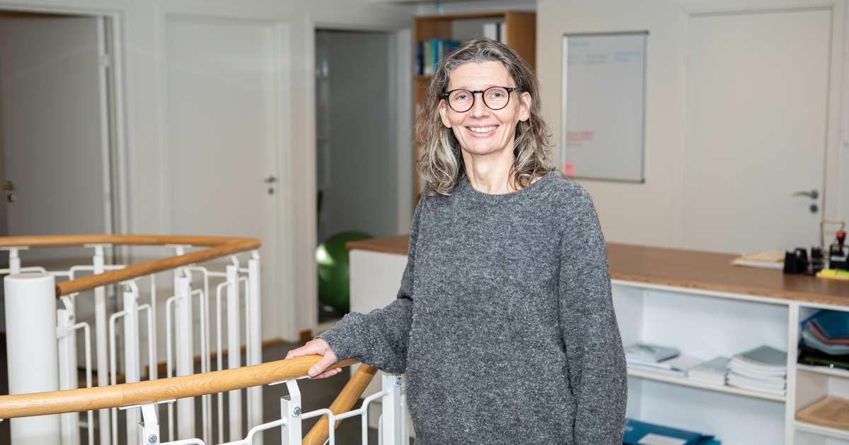 En kvinna står i kontorsmiljö och håller i ett trappräcke.